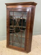 An Edwardian mahogany wall-mounted corner cabinet, moulded top over an astragal glazed panel door,