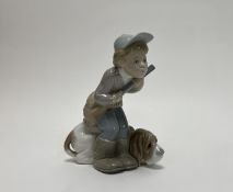 A Lladro figure of a 'Hunter Puppet', a boy holding a shotgun next to a basset hound (h. 20cm)