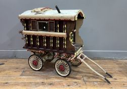 A model vintage hand-made Romani wagon with carved edges and hand-painted panels, with a fitted