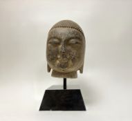 An intricately carved stone Bhuddha head, raised on a marble tapered base (h. incl base 43cm)