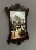 A Georgian Chippendale-style mahogany wall mirror with walnut scrolling fretwork and central