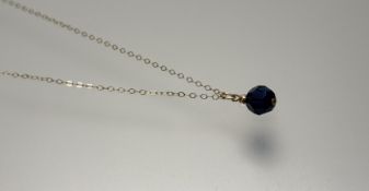A yellow metal mounted royal blue faceted bead style pendant on yellow metal trace link chain