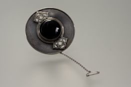 An Ola Gorie silver brooch with circular onyx cabochon entwined by pierced Celtic knots and blued