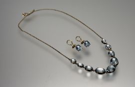 A yellow metal necklace set nine graduated aquamarine oval faceted stones mounted in rubover