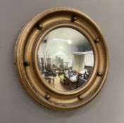 A small convex porthole-style mirror with gilt finish (d. 43cm)