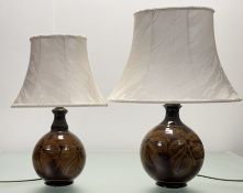 A graduated pair of baluster shaped pottery converted table lamps, decorated with a flower head
