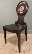 A Georgian mahogany hall chair, in the style of Gillow, with circular moulded back featuring painted