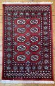 A modern hand-knotted Bokhara rug, central panel with ten guls enclosed within a border of repeating