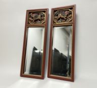A pair of Chinese wall mirrors with painted mounts and hand-carved mythological creatures to top,