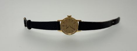 An Omega De Ville 18ct gold manual wind wristwatch with gold dial and baton hour markers on brown