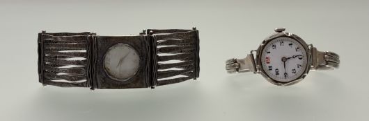 A vintage silver wristwatch with white enamel dial and Roman numerals on a white metal expanding