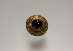 A 19thc Etruscan-style yellow metal circular brooch set central garnet cabochon: d. x 1.5cm within a
