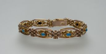 An Edwardian 9ct gold gate link bracelet set eight turquoise cabochon stones with clip fastening and