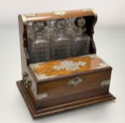 An Edwardian Oak EPNS mounted tantalus, enclosing three lob-nailed decanters, with mirror panel, and
