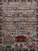 A 19thc alphabet cross-stitch sampler by Janet Crombie aged 11 1858, with house bellow enclosed