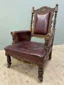 A Victorian oak-framed library armchair, carved top featuring urn and floral details flanked by