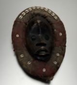 A early 20thc Dan ( Liberia / Ivory Coast) tribal carved wood mask within a fabric frame applied
