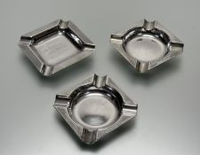 A group of three Birmingham silver sqaured table ashtrays all with engine turned decoration of