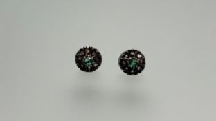 A pair of yellow and white metal stud earrings set a central circular faceted emerald