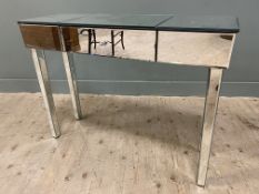 A contemporary mirrored dressing table, rectangular top over single frieze drawer raised on