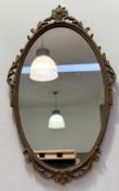 A Rococo style wooden gilt painted oval mirror, with scrolling drape trim border with flower bouquet