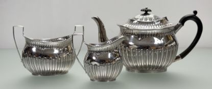 A late Victorian Birmingham silver three-piece oval half-lobed tea service with tea pot with ebony