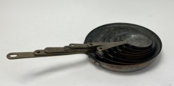 A graduating set of seven French copper and cast-iron handled frying pans (largest d. 24cm, smallest