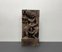 An Indian carved wooden panel of a figure holding a sword, with carved foliate detail to base (h.