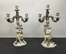 A pair of German late 19thc three-armed candlesticks moulded as figures of ladies and putti, with