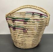 A hand-woven basket with loop handle to top, with purple and green dye design to top (h. 41cm)