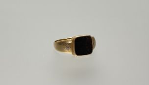 An Edwardian yellow metal signet ring set a square bloodstone flanked by star-set diamond points J/K