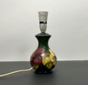 A Moorcroft pottery table lamp decorated with red and yellow hibiscus design on a green ground (h.