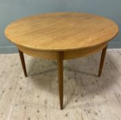 A Mid-century teak extendable dining table, circular top with leaf, raised on turned tapered