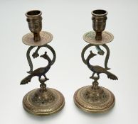 A pair of Indian ornate etched hand-painted peacock brass candleholders, raised on circular bass