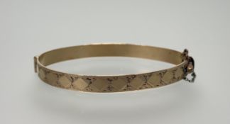 A 9ct gold metal core stiff hinged engraved bangle: d. x 6cm 10.5g