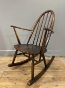 A mid-century Ercol Quaker rocking chair, arched spindle back over saddle seat and open arms, on
