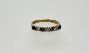 A 9ct gold ring set three round brilliant cut diamonds flanked by four round facet cut sapphires