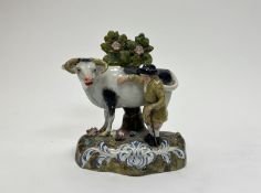 A 19thc Staffordshire pearlware figure of a farmer standing beside a cow on a green mound with