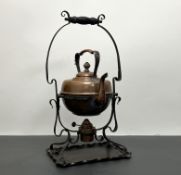 An Arts and Crafts copper kettle on a wrought-iron burner stand with shaped base (h. 47cm)