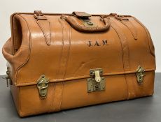A vintage American tan leather traveling suitcase with brass lock and clasps, 'J.A.M.' initials