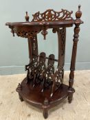 A reproduction mahogany magazine rack, shaped top with carved wood detail raised on turned