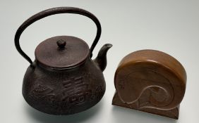 A Japanese Iron Kettle with japanese inscriptions and stylized medallions against textured ground
