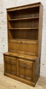 A modern two-part kitchen dresser by Ercol, carved cornice over three open plate racks, over three-