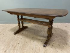 A modern elm extendable dining table by Ercol, rectangular top with curved edges, on sliding