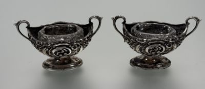 A pair of late Victorian Birmingham silver navette shaped twin handled salt sellers with rococo