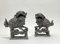 A pair of Chinese cast bronze foo dog temple incense burners with pup, raised on pierced bases (h.