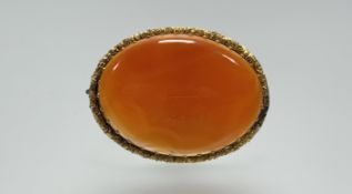 An Edwardian yellow metal oval brooch set cornelian enclosed by a rose and leaf border: h. x 3.5cm