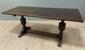 A 1920's oak refectory style dining table, plank top raised on twin carved baluster supports on