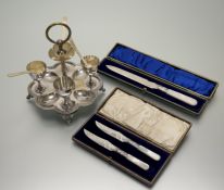 An Edwardian epns egg eperign with loop handle and four screw in egg cups on four splay feet with