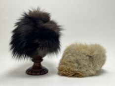 A fox fur pom-pom hat in brown, with silk lining and elastic headband, together with a lighter tan
